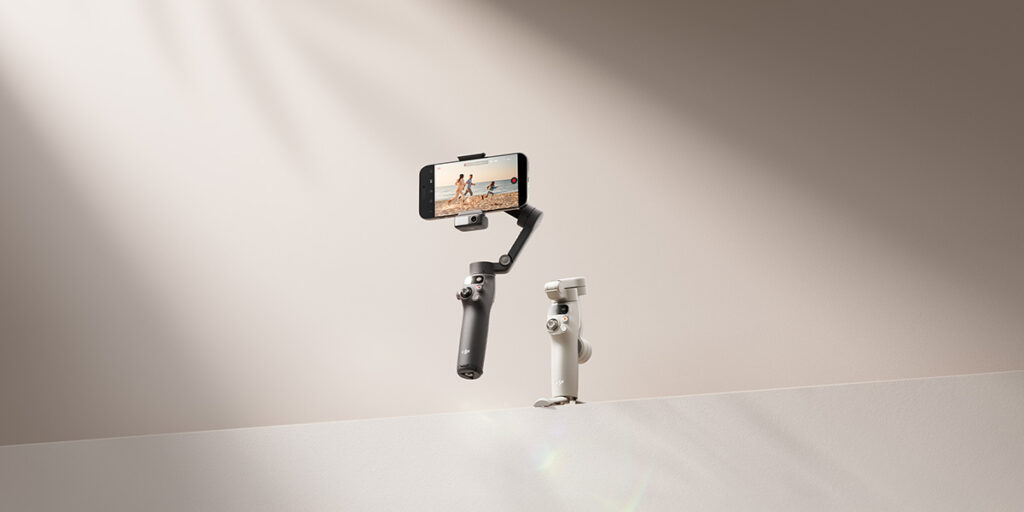 Gimbal DJI Osmo Mobile 7P z zamontowanym smartfonem i gimbal DJI Osmo Mobile 7 na brązowym tle.