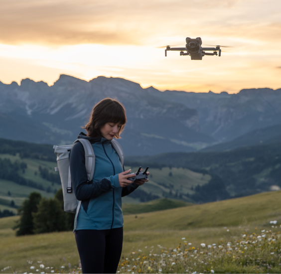 Turystka latająca dronem w górach o zachodzie słońca