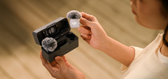 Kobieta wyjmuje biały nadajnik DJI Mic Mini 2 z etui