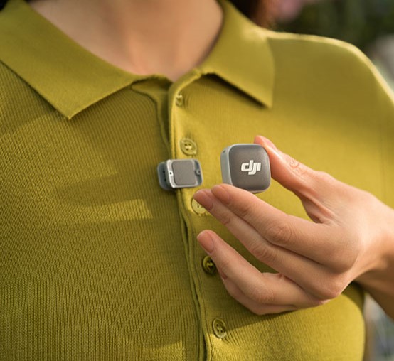 Kobieta przypina nadajnik DJI Mic Mini 2 do bluzki