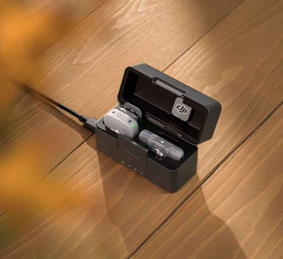 Etui ładujące DJI Mic Mini 2 z nadajnikiem i odbiornikiem na drewnianym stole