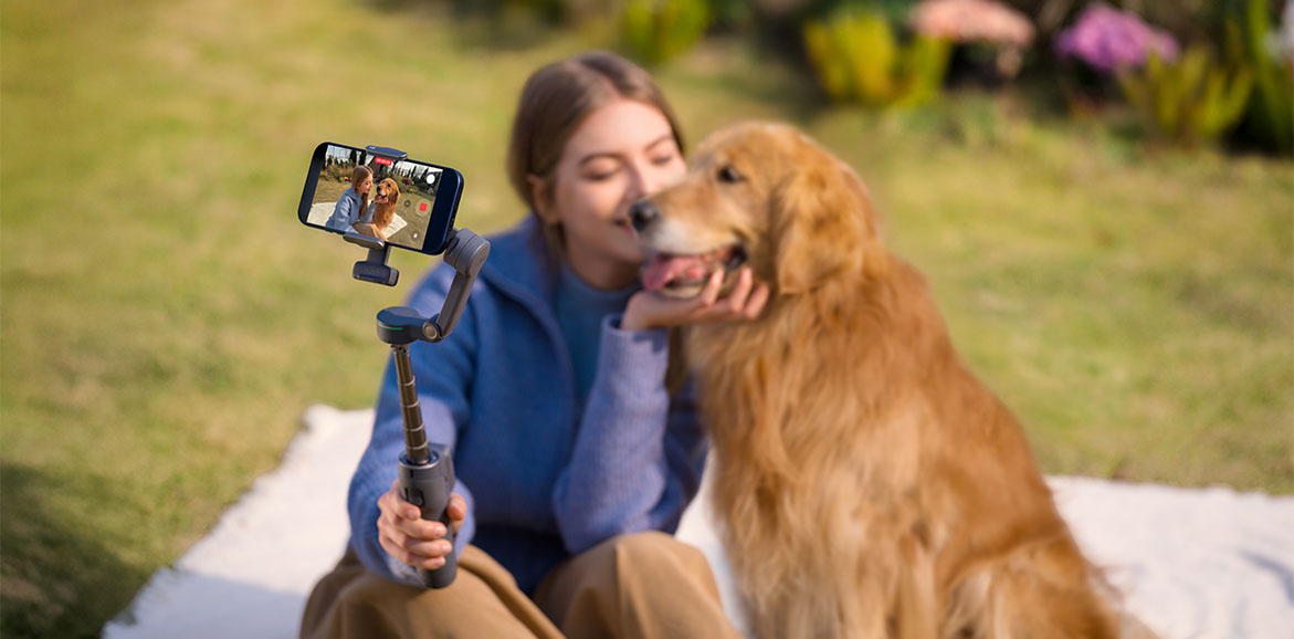 Dziewczyna robi sobie selfie z psem za pomocą smartfona na gimbalu