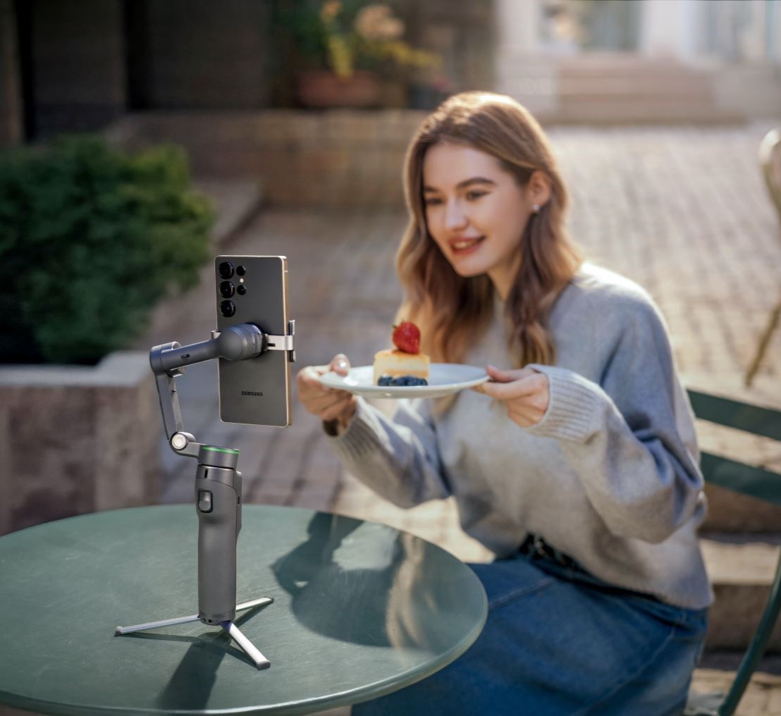 Dziewczyna pokazuje do kamery smartfona na gimbalu ciastko