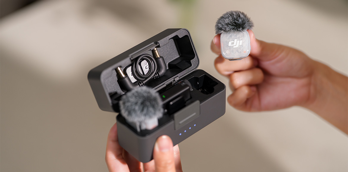 Dłonie trzymające nadajnik DJI Mic Mini 2 i etui ładujące