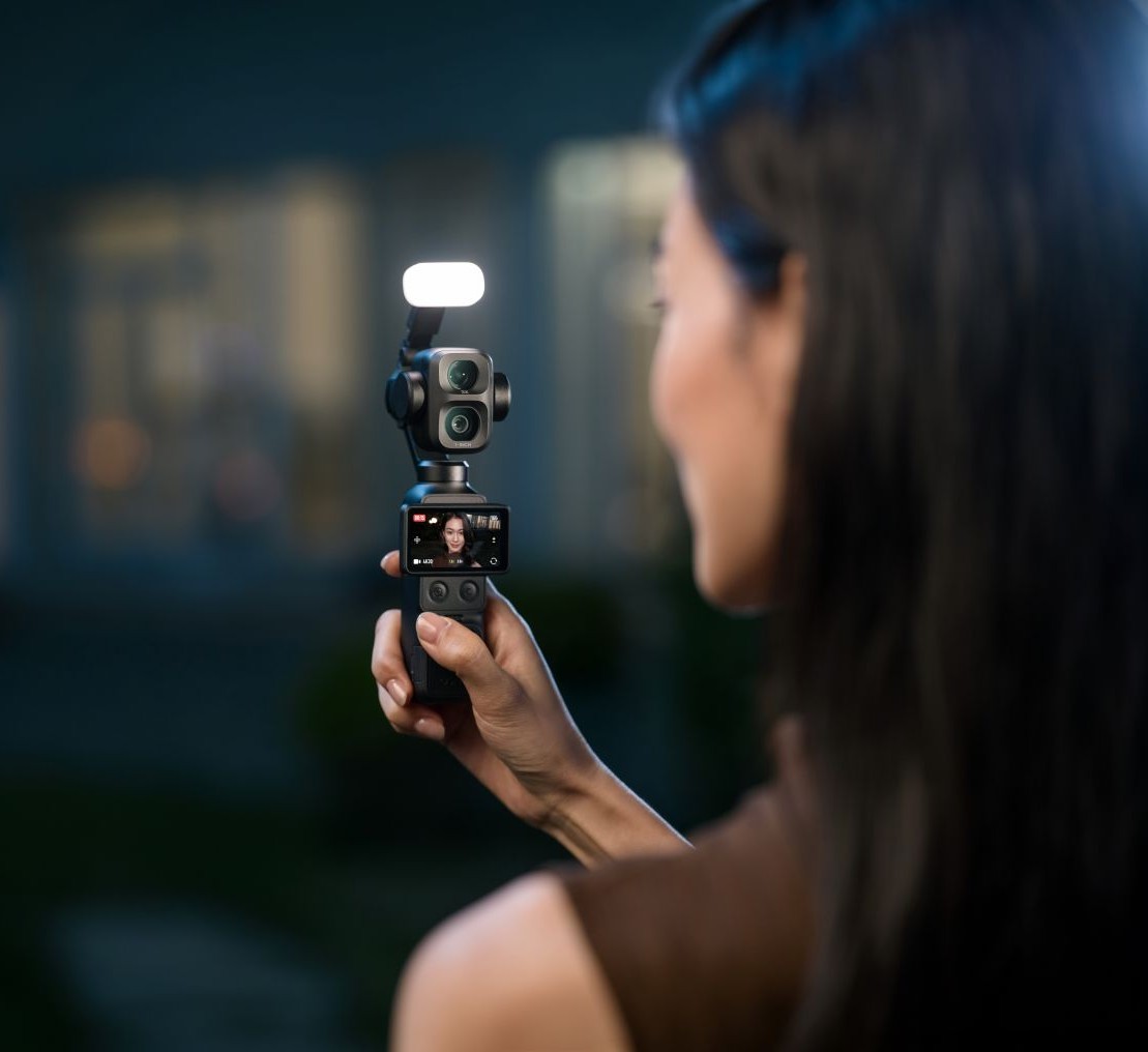 Kobieta trzymająca kamerę DJI Osmo Pocket 4P z lampą doświetlającą w nocy