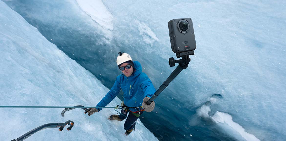 Mężczyzna wspina się po lodowej górze i nagrywa film kamerą DJI Osmo 360 II