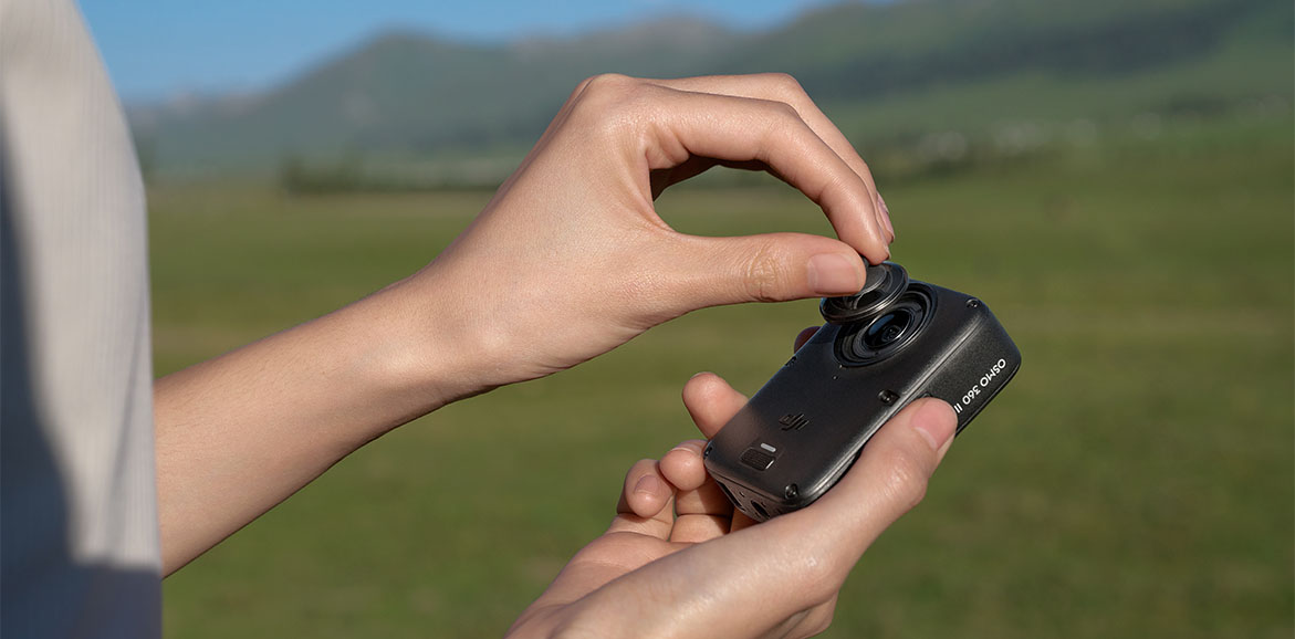 Zbliżenie na dłonie, które wymieniają obiektyw kamery DJI Osmo 360 II