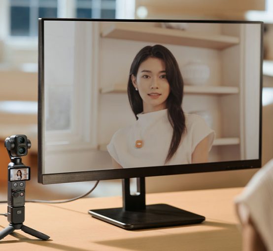Kobeta w trakcie wideorozmowy przed monitorem i kamerą DJI Osmo Pocket 4P