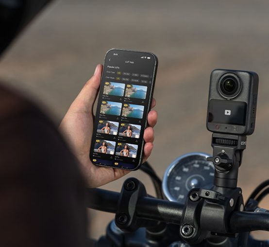 Motocyklista obrabia na telefonie wideo, a na kierownicy na przymocowaną kamerę DJI Osmo 360 II